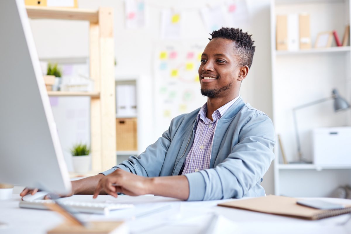 A man smiling at a computer screen.